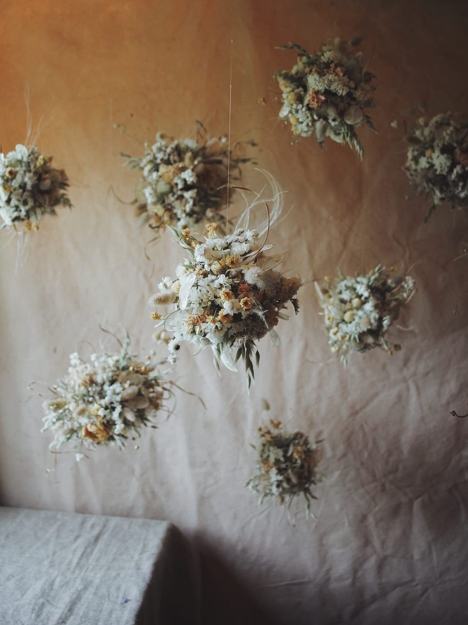 Dried floral arrangements hanging on a textured wall.